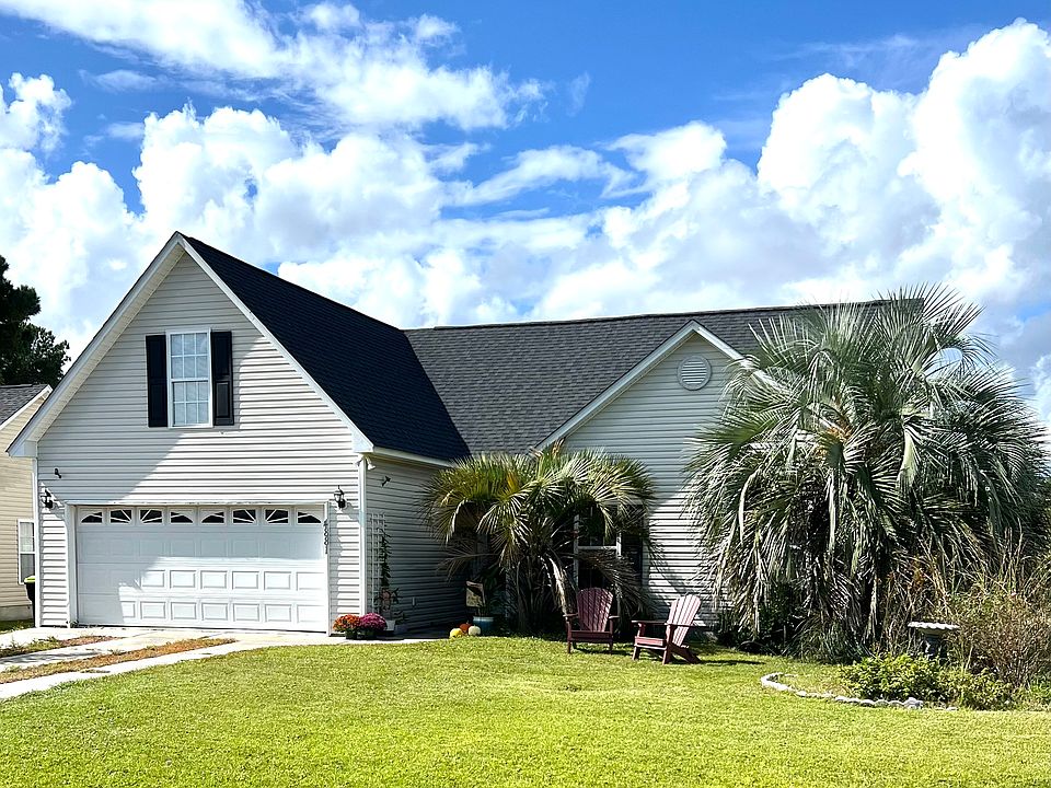 Exterior of home. Large, grassy yard and large driveway.