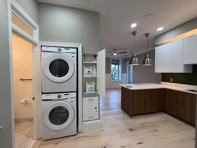 Entryway facing full size washer/dryer with guest bathroom to the left