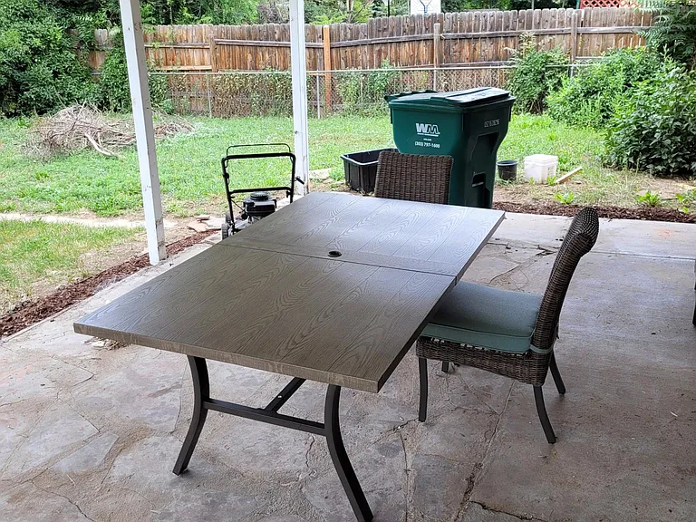 Large covered back patio with string lighting and spacious fenced-in yard.