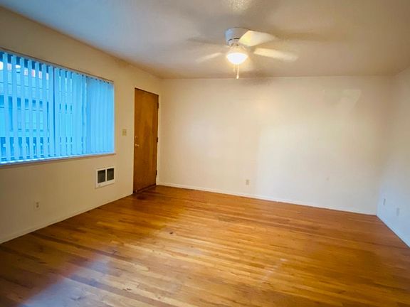 Spacious living room with large window to allow in lots of natural light and ceiling fan with light.
