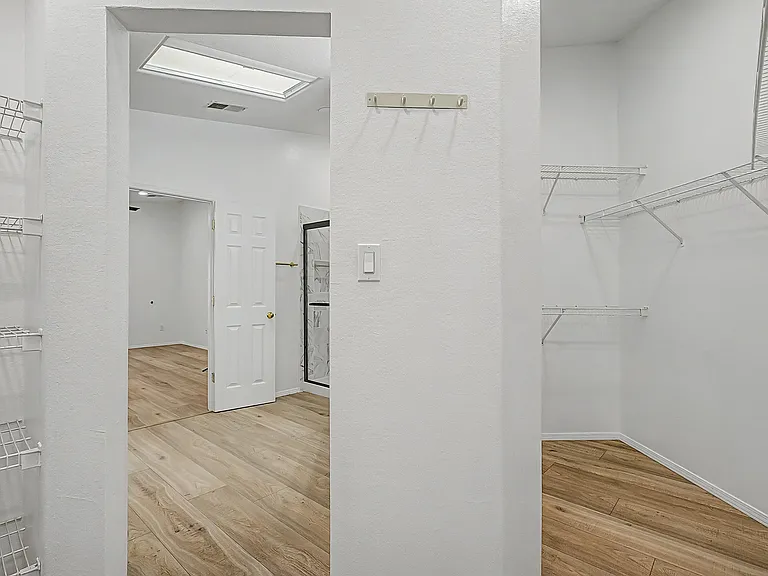 Walk-in closet and view to primary bathroom.