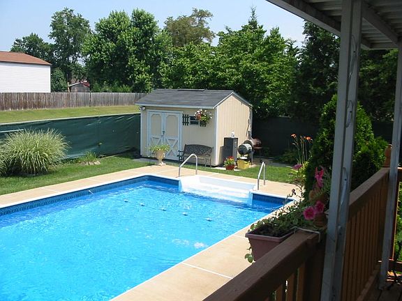 This photo is a bit old. The chain link fence was replaced a couple years ago with vinyl. Otherwise, the pool still lies where it is. Lots of summer sun. Shed has also been remodeled, and repainted.