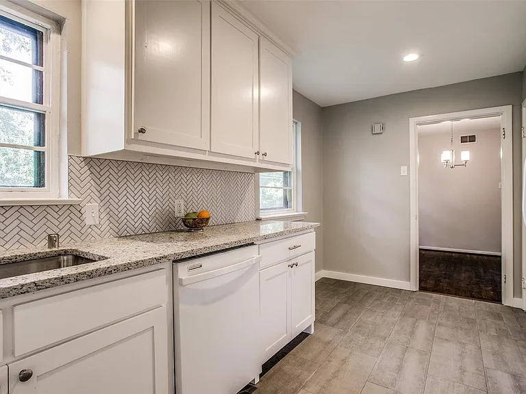 Kitchen featuring white shaker cabinetry, speckled countertops, a herringbone tile backsplash, and a stainless steel sink with a gooseneck faucet