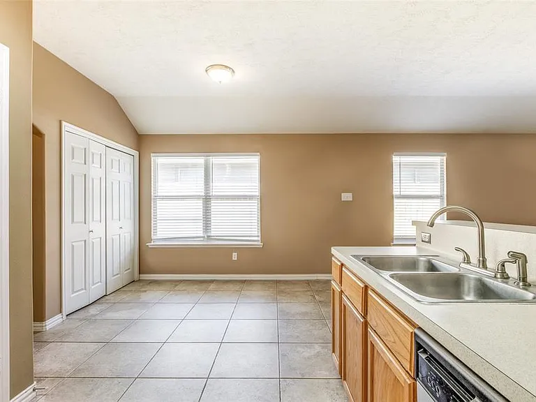 Dining Area is convenient to kitchen. Generous natural light illuminates dining and kitchen areas. Venetian blinds cover all windows.