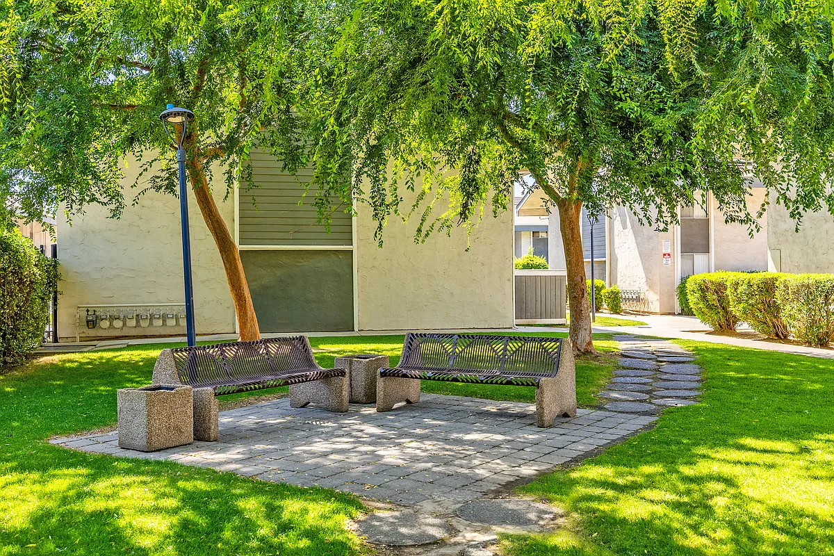 Tranquil courtyard with shaded seating. - Fountain West Apartments