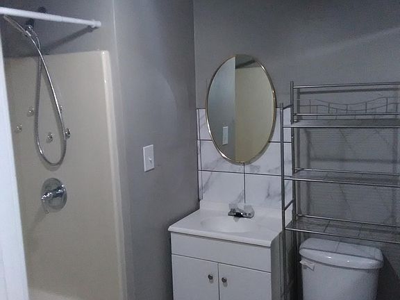 Bathroom, tile floor,storage stand behind toilet, another large mirror hanging on the wall, very large shower base