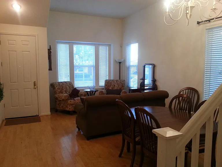 East-facing front doors and large windows flood the space with morning sun. The expansive living and formal dining area features an elegant chandelier and creates the perfect room for a piano acoustic.
