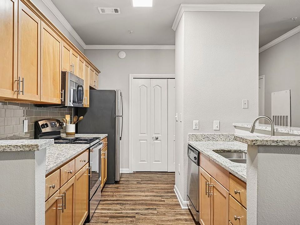 Kitchen with oak cabinetry, speckled granite countertops, stainless steel appliances, and hard surface flooring