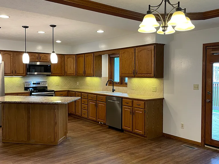 Kitchen with stainless steel appliances, island with electric and room for seating.