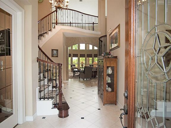 Spectacular front entrance boasts a stunning curved wrought iron staircase, high ceiling with crown molding and lovely tile floor.