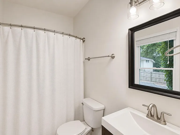 Full bathroom with shower/tub combo, curved curtain rod, vanity sink, and a window for natural light and ventilation.