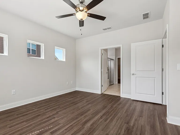 Bedroom with wood floors and a ceiling fan.