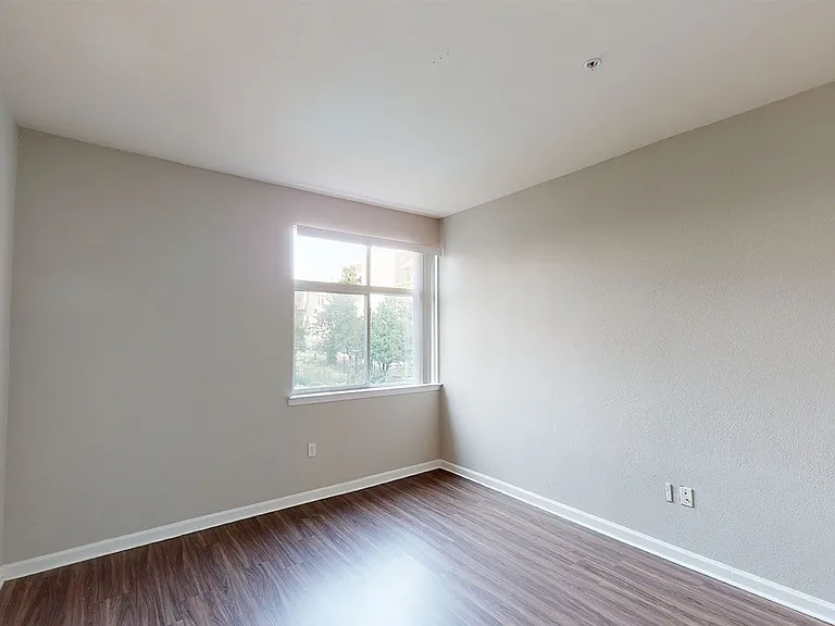 Spacious apartment bedroom with wood-style flooring.