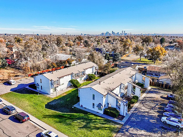 Charming apartment complex surrounded by lush greenery, offering picturesque views of city skyline and vibrant neighborhood.