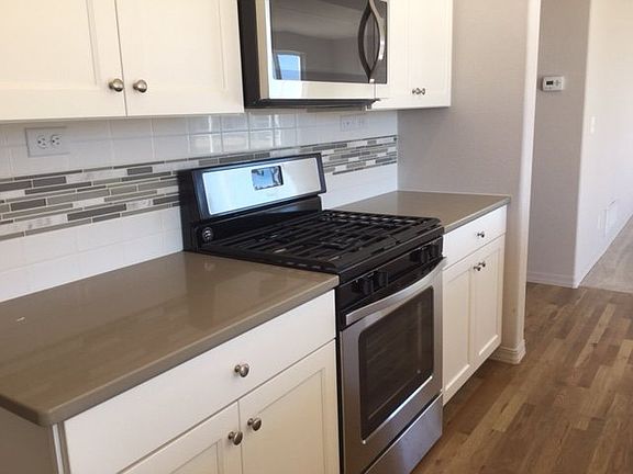 Stainless steel appliances including gas range and custom tile backsplash complete this beautiful kitchen. (Photo of home under construction)