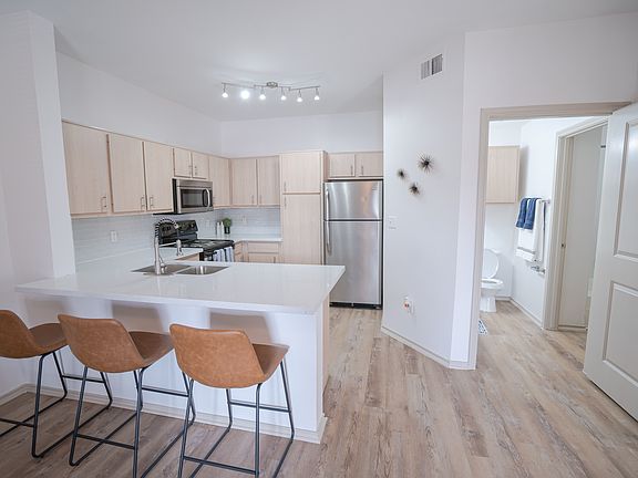 Kitchen w/ stainless steel appliances, quartz counters, and tile backsplash