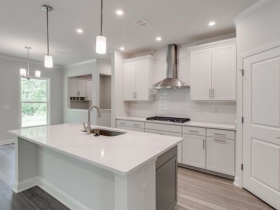 A bright, gourmet kitchen equipped with pendant fixtures and beautiful luxury vinyl plank flooring.