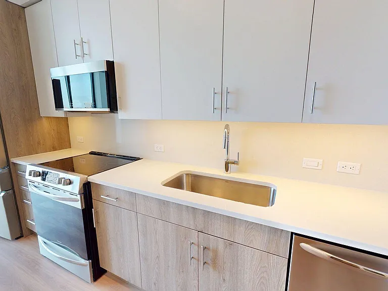 Apartment Kitchen with Stainless Steel Appliances, white countertops and wood style flooring