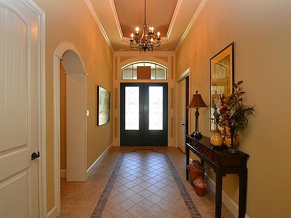 Entry offering double front doors with iron rail accents, tile floors, raised ceilings and double cr