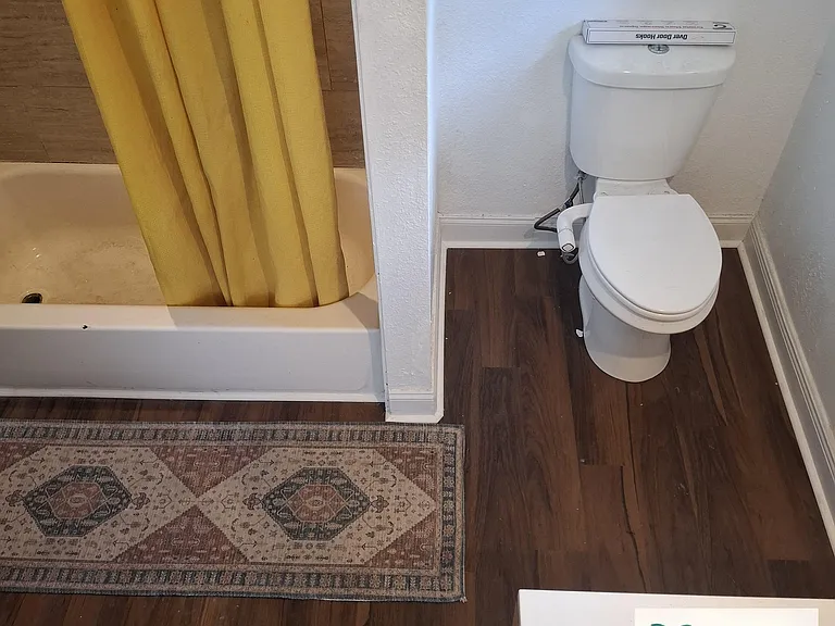 Bathroom with a tub/shower combo, shower curtain, and easy-care flooring for simple cleanup.