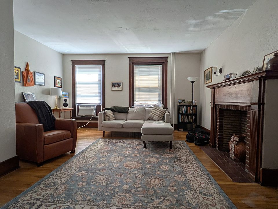Large living room overlooking Main St with an ornamental, original fireplace