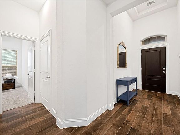 Entryway featuring wood-finish flooring, a dark wood paneled door with an arched transom window, and a recessed ceiling element