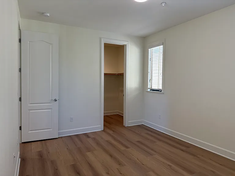 Spacious Bedroom #2 features multiple windows, vinyl flooring, walk-in closet, a separate bathroom sink and share a Jack-and-Jill style bathroom for the bathtub and toilet.