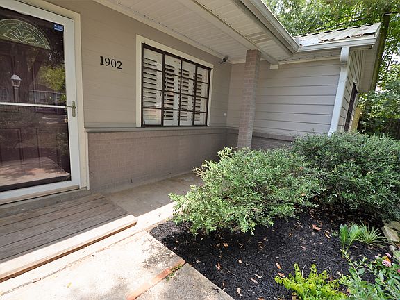 Convenient front porch sitting area surrounded by lush greenery, offering a welcoming and private feel.