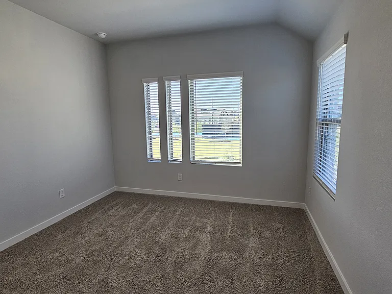 Sun-filled upstairs bedroom featuring large windows with a direct, scenic view of the community park