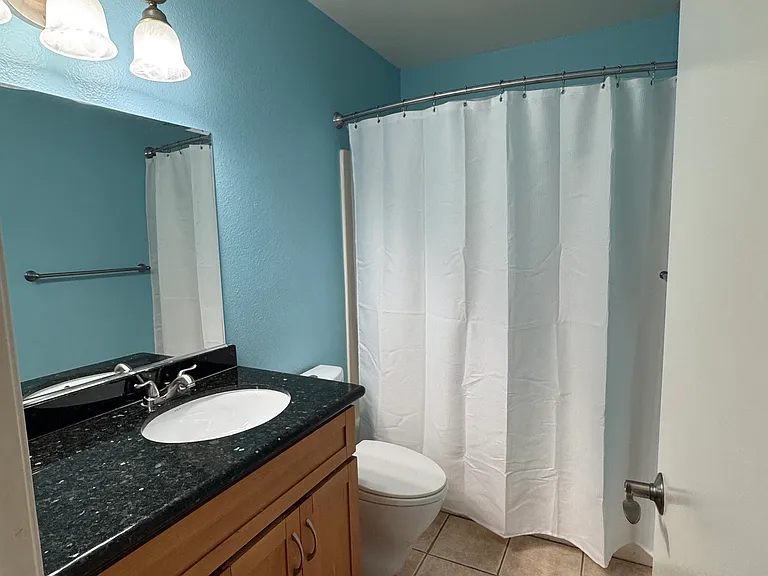 Full second bathroom with a granite-top vanity, new medicine cabinet, and curved shower rod over the bathtub/shower