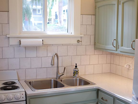 Kitchen with new stove, new fridge, new quarts countertop and stainless steel sink with freshly renovated cabinets with under- and over-cabinet lighting