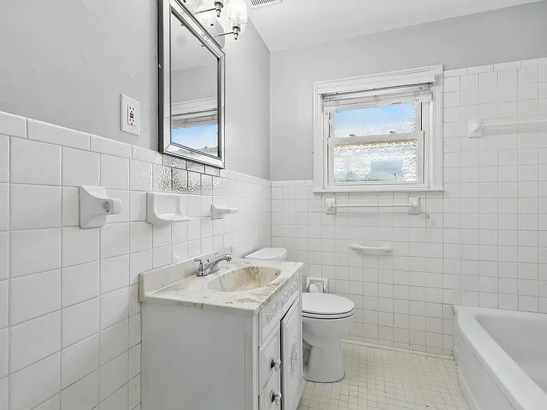 Bathroom with full tile wainscoting and coordinating tiled flooring