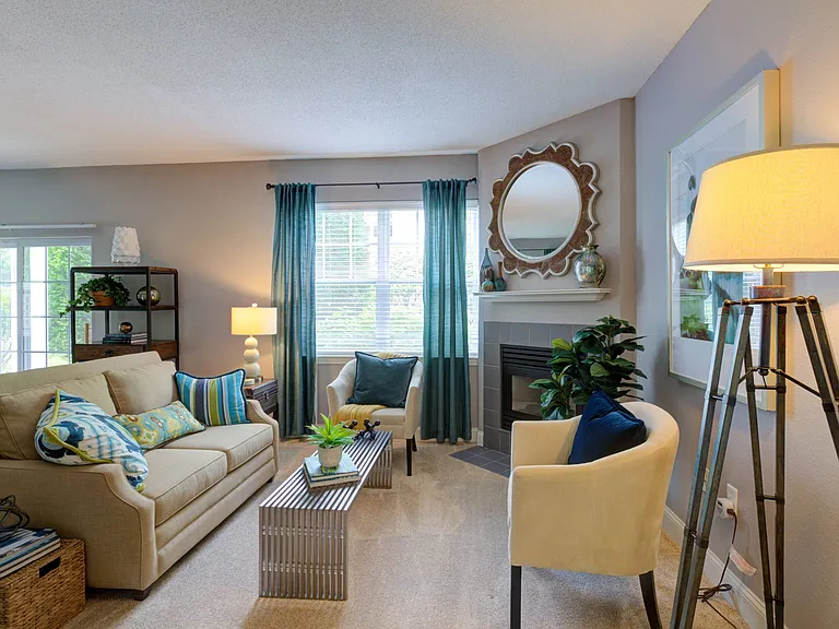 Spacious living room with couch, two chairs and coffee table arranged in front of fireplace. Large windows provide natural light.