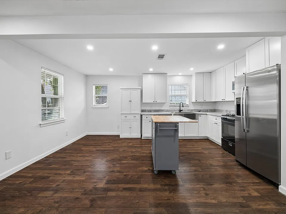 Expansive kitchen and eating area with island, gas range, dishwasher, and side by side refrigerator.