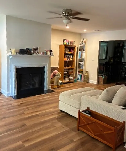 Spacious living area with ceiling fan, gas fireplace logs, recessed lighting.
