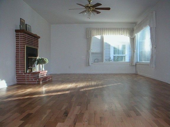 Large living room is bright & cheery, beautiful hardwood floors, brick fireplace has gas insert.