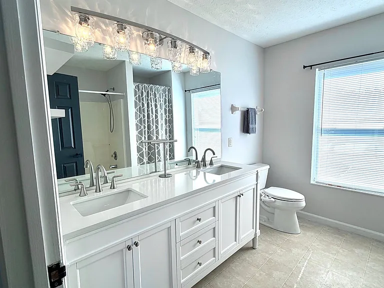 En-suite primary bath with large window for lots of light. New double bowl vanity with marble top and new modern lighting.