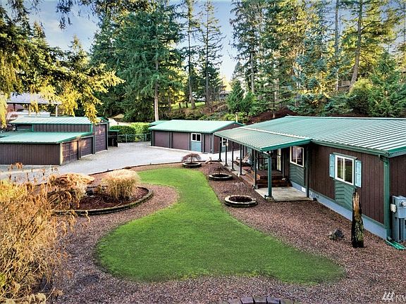 View from right side of home showing off sculpted yard, multiple Japanese Maples, front covered walkway leading to 2 Garages with 7 total bays. Bring your vehicles/toys/yard equipment/hobbies that can all be protected inside. Garage on right is heated + connected to cable & internet!