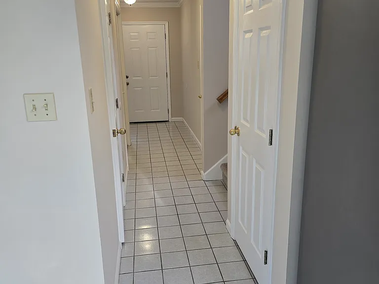 Hall from kitchen to powder room, large hall closet, garage entry and stairs to upper level. Extra storage area under the stairs.