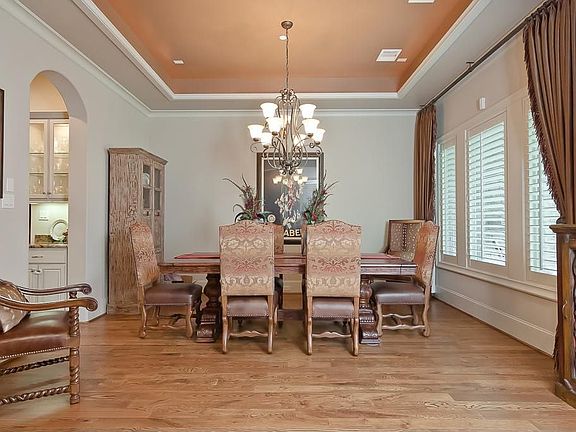 Elegant formal dining has hardwood floors, coffered ceiling with cove lighting, and decorative light