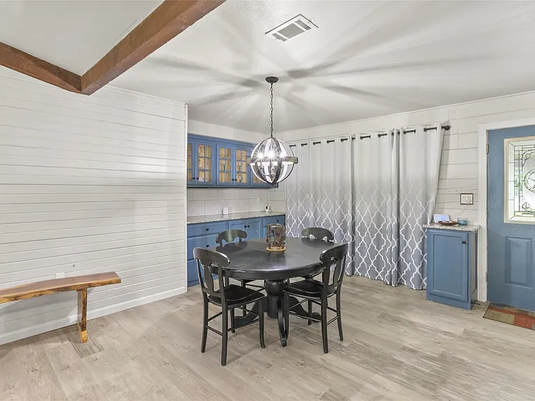 Dining area featuring light wood-finish flooring, white shiplap walls, and exposed ceiling beams