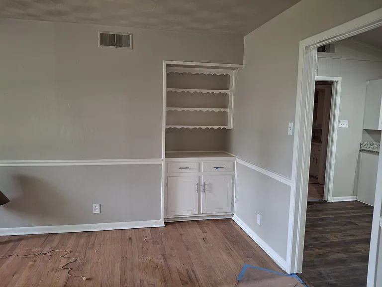 Front room view from entrance hallway. Hardwood floor. Built in storage unit. To right is passage to dining/breakfast room and kitchen