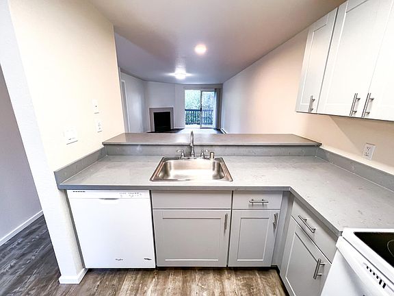 View from kitchen to living/dining room and to the balcony overlooking the trees.