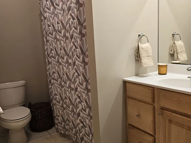 Newly decorated bathroom with ceramic tile floor. Standard size bathtub. Maple cabinets.