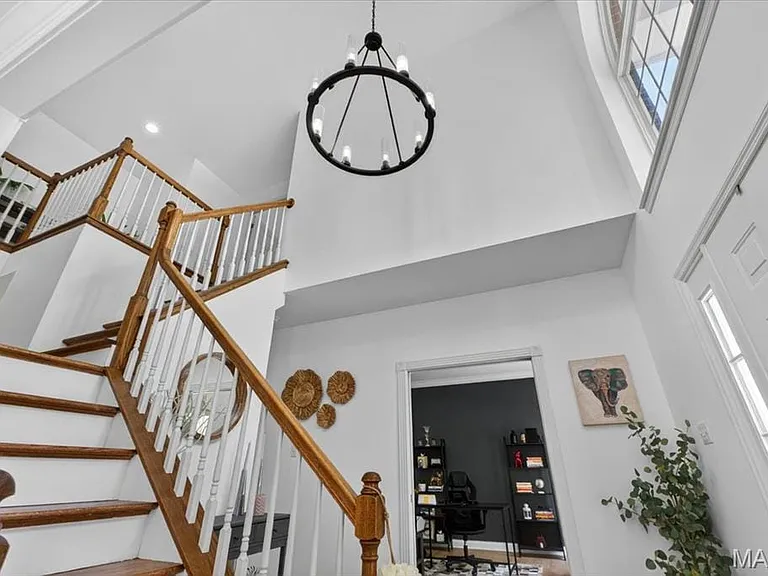 Two-story foyer featuring a grand staircase with wood treads and white balusters