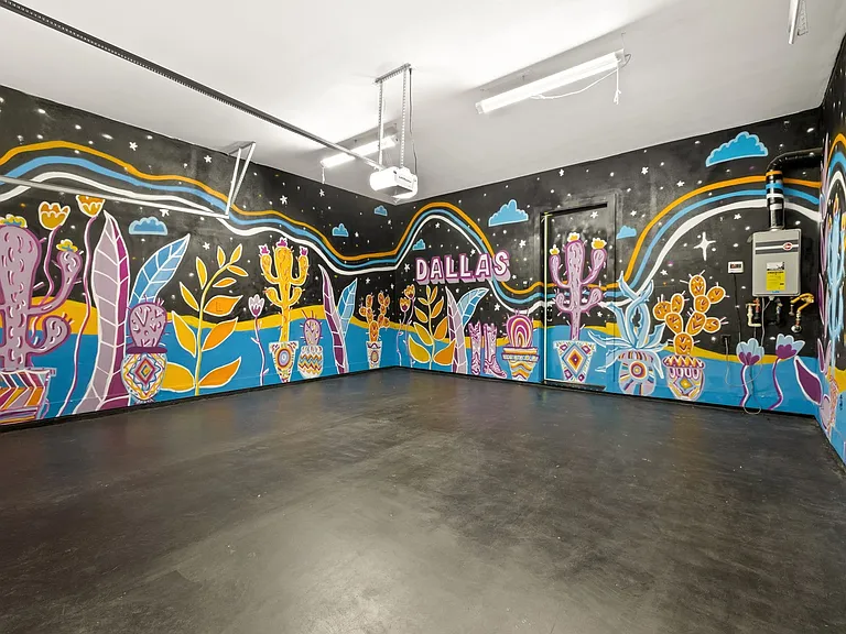 Spacious interior featuring a vibrant, multi-color mural, concrete flooring, and overhead fluorescent lighting