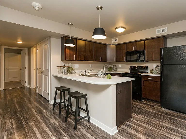 Modern cherry cabinets, a functional breakfast bar, and a seamless layout create a warm and welcoming kitchen space.