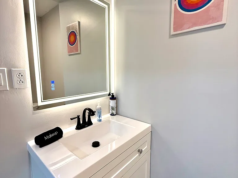 The bathroom features a beautiful modern mirror with amazing backlighting, along with various lighting options to suit your needs. The vanity provides additional storage, making this space both functional and stylish.