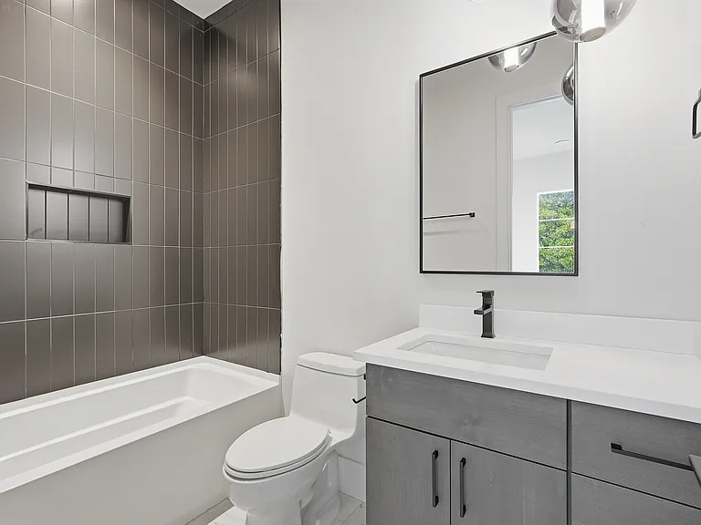 Modern bathroom with sleek vanity, tiled shower/tub combo, and contemporary finishes.
