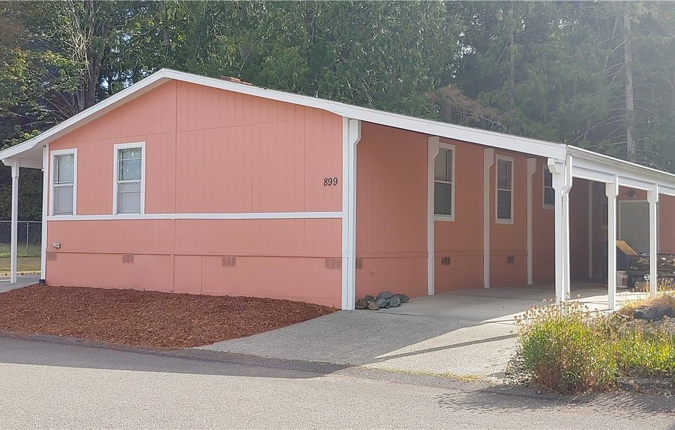 1997 Golden West home with 2 large decks and a deep carport with storage for outdoor tools or hobbies.